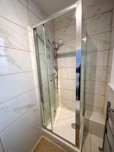 a shower with a glass door in a bathroom at Pink Door Guesthouse in London