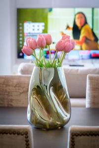 雅典的住宿－Stylish 2BR flat with stunning views & prv parking，一张桌子上装有粉红色花的花瓶