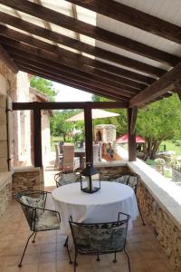 een patio met een witte tafel en stoelen aan een stenen muur bij Beautiful Home with Large Gardens and Heated Pool in Sauveterre-la-Lémance
