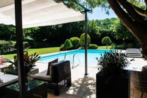 een patio met een zwembad en een witte parasol bij Beautiful Home with Large Gardens and Heated Pool in Sauveterre-la-Lémance