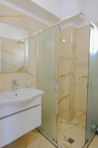 a bathroom with a glass shower and a sink at Eleni Guest House in Sarandë
