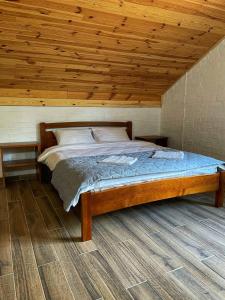 a bed in a room with a wooden ceiling at Садиба Бабина Лоза in Lisove