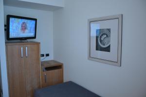 a room with a television and a cabinet with a picture at Albergo Alla Posta in Trieste