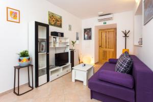 a living room with a purple couch and a tv at Nila's Place in Dubrovnik