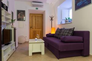 uma sala de estar com um sofá roxo e uma televisão em Nila's Place em Dubrovnik