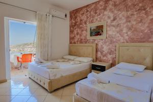 two beds in a room with a balcony at Eleni Guest House in Sarandë