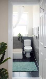 a bathroom with a toilet and a tub and a window at LFC Stadium Apartment 2 in Liverpool