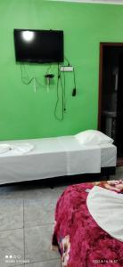 諾布里斯的住宿－Pousada Canto das Araras - Vila Bom Jardim Nobres MT，绿色的客房设有两张床和墙上的电视。