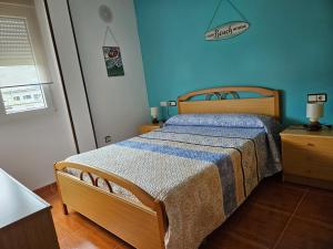 1 dormitorio con 1 cama con pared azul en Apartamento en Laxe, Costa da Morte, en Laxe