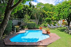 een zwembad in een tuin met stoelen en bomen bij The Coach House in Franschhoek