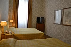 a hotel room with two beds and a television at Albergo Alla Posta in Trieste