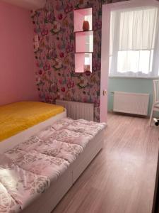 ein Schlafzimmer mit einem Bett und einer rosa Wand in der Unterkunft Good J&I apartment in Balvi