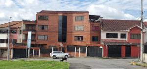a white truck parked in front of a brick building at Departamento en Cuenca, 2 habitaciones y parqueo gratis in Cuenca