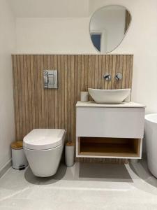 een badkamer met een toilet, een wastafel en een spiegel bij Brand New Luxury 2 Bedroom House in Parkstone