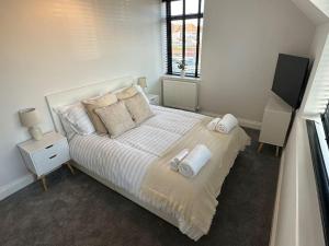 a white bedroom with a bed with towels on it at Brand New Luxury 2 Bedroom House in Parkstone