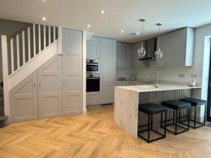 een keuken met witte kasten en een bar met barkrukken bij Brand New Luxury 2 Bedroom House in Parkstone