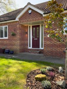 a brick house with a red door and a yard at Stunning Beverley Bungalow w Fireplace, private parking, and garden in Beverley