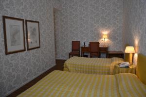 a hotel room with two beds and a dining room at Albergo Alla Posta in Trieste