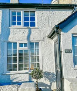 a white building with a window and a potted plant at SEREN cottage by the sea in Llangadwaladr