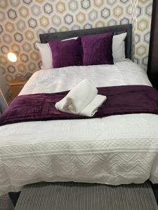 a large bed with purple and white sheets and pillows at Luxury Spacious 2 Bedroom Home. in Liverpool