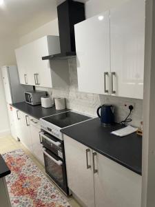 a kitchen with white cabinets and a black counter top at Luxury Spacious 2 Bedroom Home. in Liverpool