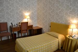 a hotel room with a bed and a desk at Albergo Alla Posta in Trieste