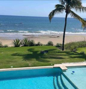 a swimming pool next to a beach with a palm tree at Casa de la Amor Casita in Pedasí Town