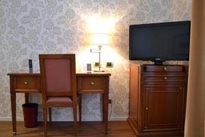 a room with a tv and a desk and a chair at Albergo Alla Posta in Trieste