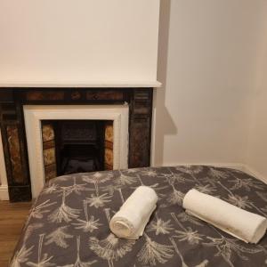 a bed with two towels on it with a fireplace at 41 Crawley Road in Luton