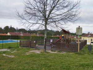 a playground with a wooden fence and a tree at Apartamento Morriña in Brion