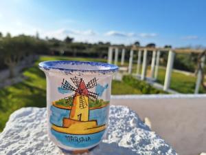 eine Tasse mit einem Bild einer Windmühle auf dem Tisch in der Unterkunft Villa Edo in Marsala