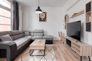 een woonkamer met een bank en een tv bij Magnifique maison pleine de charme ideale jeux olympiques un kilometre de la gare in Évreux