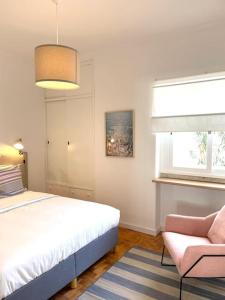 una camera da letto con un letto, una sedia e una finestra di Costa Beach a Costa da Caparica