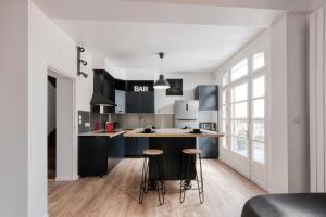 een keuken met zwart-witte kasten en krukken bij Magnifique maison pleine de charme ideale jeux olympiques un kilometre de la gare in Évreux