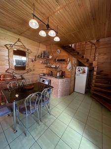 a kitchen with a table and chairs and a refrigerator at Cottage 'Carolina' with hot tub, sauna and BBQ area in Kosiv