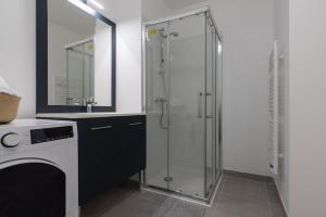 a bathroom with a glass shower and a sink at Cocon Décinois Groupama parking Balcon Eurexpo in Décines-Charpieu