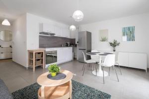 a large white kitchen with a table and chairs at Cocon Décinois Groupama parking Balcon Eurexpo in Décines-Charpieu