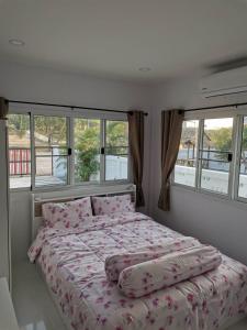 a bedroom with a bed with pink sheets and windows at S&F villa in Sam Roi Yot