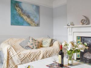 Sala de estar con sofá y mesa con botella de vino en Dune-cottage en Caister-on-Sea