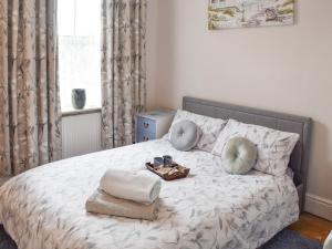 Una cama con almohadas y una bandeja de comida. en Dune-cottage en Caister-on-Sea