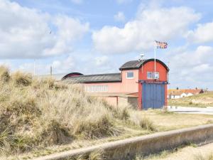 a red building on a hill with a flag on it at Dune-cottage in Caister-on-Sea