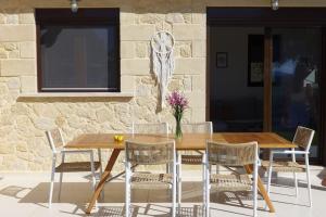 a wooden table and chairs with a table and a stone wall at Stone Villa Analisa, Pool, BBQ, Sunset Sea view in Kondomárion
