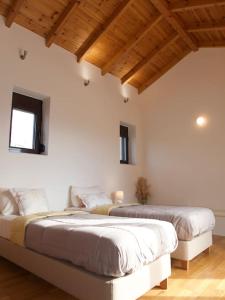 two beds in a room with white walls and wooden ceilings at Stone Villa Analisa, Pool, BBQ, Sunset Sea view in Kondomárion
