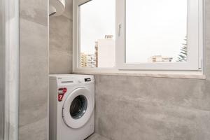 uma máquina de lavar roupa na casa de banho com uma janela em Costa Dream em Costa da Caparica