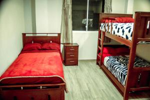 1 dormitorio con 2 literas con sábanas rojas en Casa de Campo - Baños de Agua Santa, en Juivi