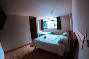 Habitación pequeña con cama y ventana en Chacraraju Hostel, en Huaraz