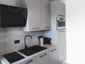 een keuken met witte kasten, een wastafel en een magnetron bij Sea View Garden Apartment K2 in Rabac