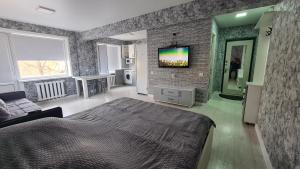 Сдаётся однокомнатная квартира возле озера في بالخاش: غرفة نوم بسرير وتلفزيون على جدار من الطوب