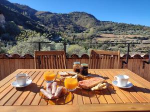 a wooden table with breakfast foods and orange juice on it at Casa Pes 