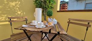 einen Holztisch mit Tassen und Untertassen darauf in der Unterkunft Dimora Mia in Roseto degli Abruzzi